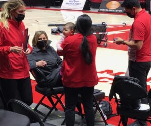 Malia Shoji works while holding her baby at the Huntsman Center.