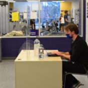 A man sits at a desk, typing on a computer.