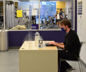 A man sits at a desk, typing on a computer.