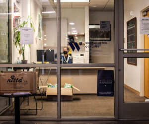 Woman sits in office with large glass windows