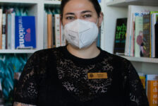 Kaitlyn Mahone, the owner of Under the Umbrella, a queer bookstore, stands in front of their favorite section in the store, the nonfiction section on Feb. 26.