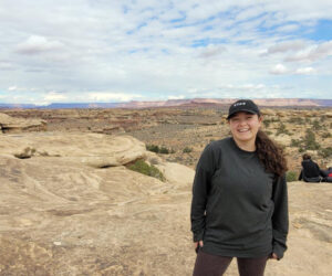 Shellby Carvalho, a female student, stands outside, poses on top of a rock structure in Canyonlands, Utah.