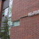 A red brick building with the words "Meldrum Science Center" and a green pine tree out front on a grey cloudy day.