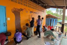 Nine Westminster students paint an image of a tree and a snake on the wall at a school in Thailand.