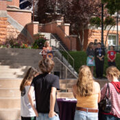 President Beth Dobkin stands behind a lectern on the stairs in front of Converse Hall while contributors to this partnership stand beside her to the right.
